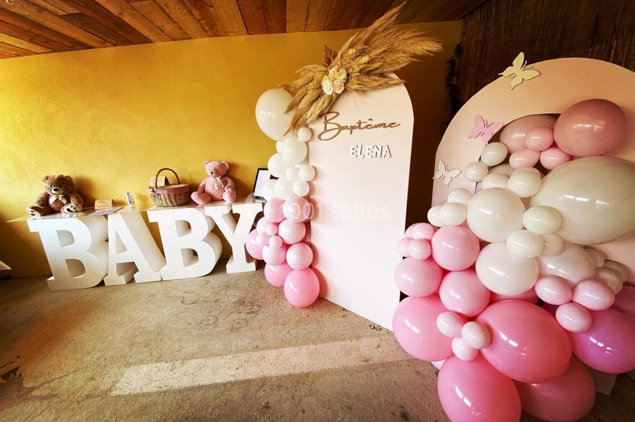 Décoration de baptême avec ballons roses et blancs, lettres géantes ’BABY’, peluches et panneau personnalisé.
