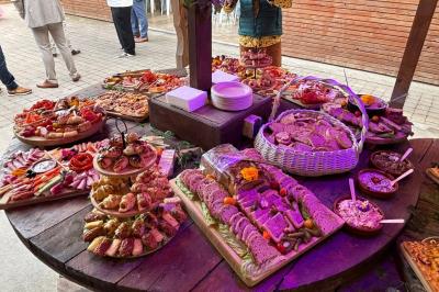 Table en bois garnie de divers plats, pains, charcuteries et amuse-bouches, présentés pour un buffet en extérieur.