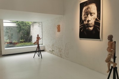 Façade d'une maison moderne en bois avec de grandes baies vitrées, entourée de murs en briques et végétation.