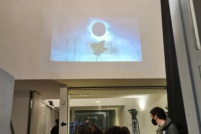 Façade d'une maison moderne en bois avec de grandes baies vitrées, entourée de murs en briques et végétation.