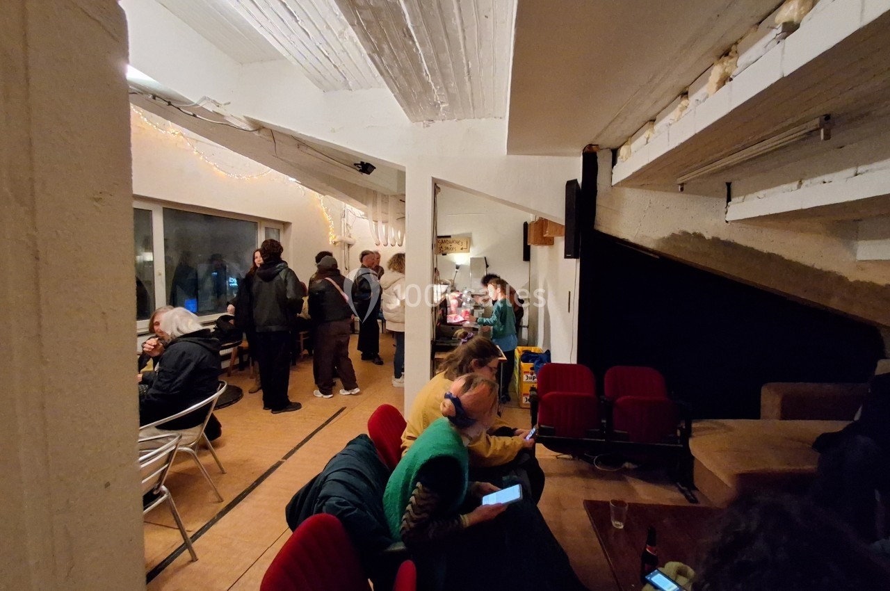 Personnes rassemblées dans une salle lumineuse, certaines assises et d'autres debout près d'un buffet.