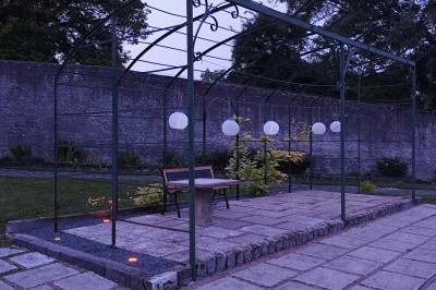 Miniature Location salle Chaptuzat (Puy-de-Dôme) - Château des Bérangers #17 Allée bordée de jeunes arbustes menant à une porte en fer, entourée d'arbres et d'un espace herbeux.