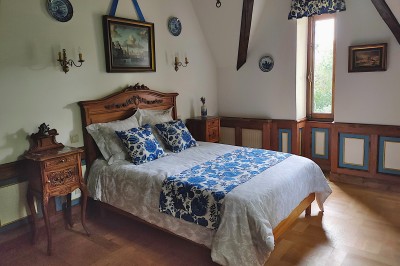 Miniature Chambre Flamande Allée bordée de jeunes arbustes menant à une porte en fer, entourée d'arbres et d'un espace herbeux.