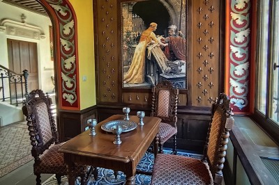 Miniature Salon des Chevalier Allée bordée de jeunes arbustes menant à une porte en fer, entourée d'arbres et d'un espace herbeux.