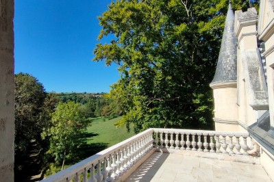 Miniature Terrasse haute Allée bordée de jeunes arbustes menant à une porte en fer, entourée d'arbres et d'un espace herbeux.