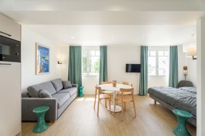 Terrasse avec deux chaises, une table basse, des panneaux décoratifs et vue sur un jardin et des maisons.