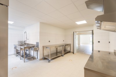 Salle de bain moderne avec douche vitrée, lavabo sur meuble noir et miroir rond éclairé.