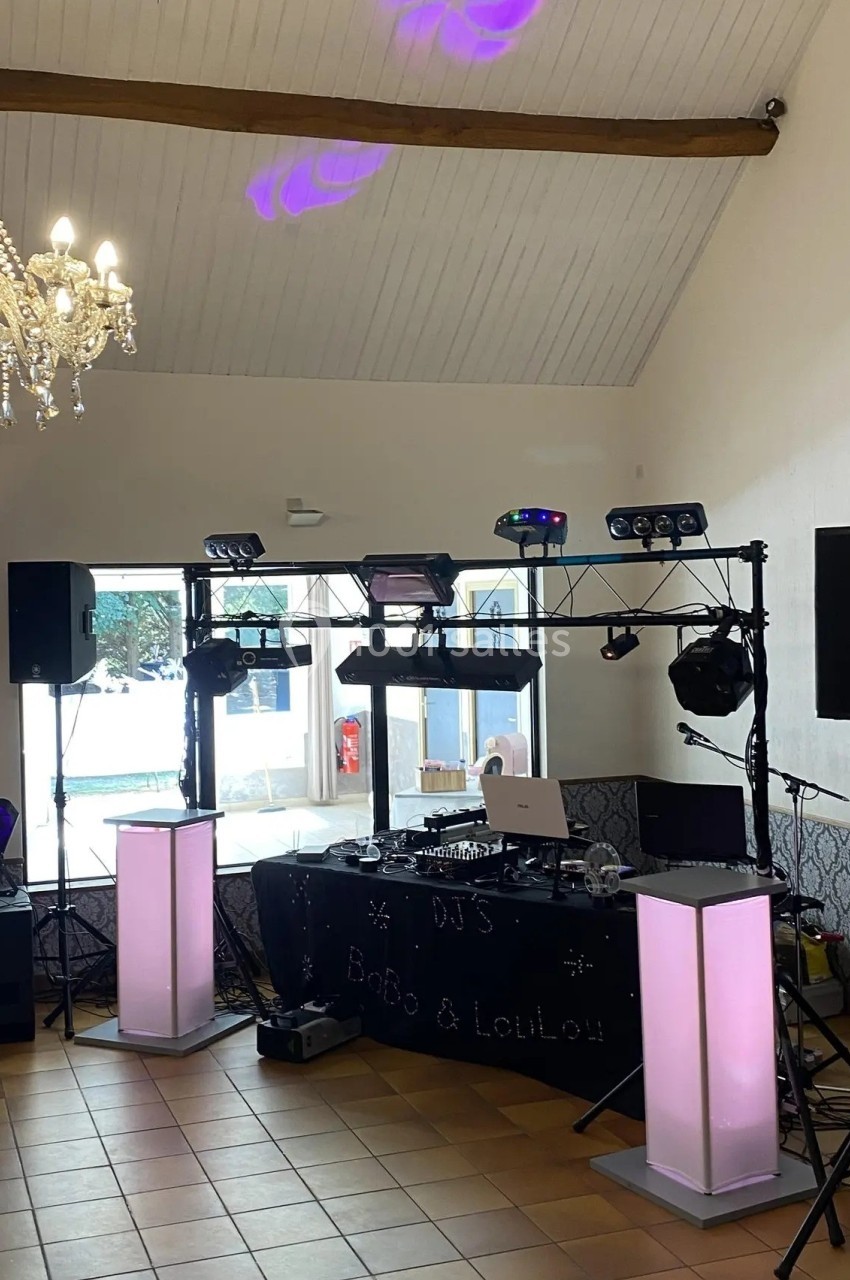 Installation de matériel de sonorisation et d'éclairage dans une salle avec un lustre et un plafond en bois.