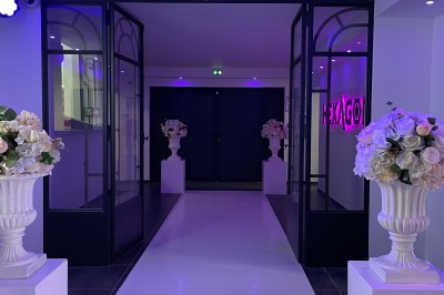 Escalier intérieur éclairé par des lumières au sol, avec une rampe et une porte en fer forgé décorative.