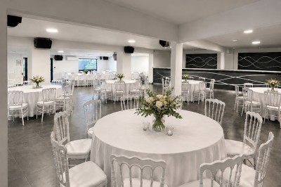 Miniature Salle PRESTIGE Salle de réception décorée avec des tables rondes, nappes blanches, chaises assorties et arrangements floraux élégants.