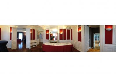 Salle élégante avec tables rondes et chaises blanches, décorée de bouquets, éclairée par des luminaires modernes.