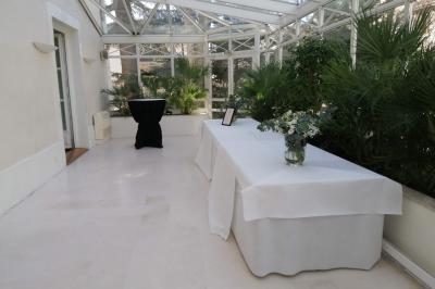 Salle élégante avec tables rondes et chaises blanches, décorée de bouquets, éclairée par des luminaires modernes.