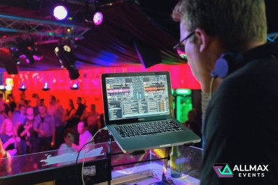 Main posée sur une table de mixage avec des boutons et des lumières floues en arrière-plan.