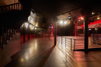 Miniature Amphithéâtre sans fauteuils Intérieur d'une salle de spectacle avec balustrade, colonnes décoratives et éclairage tamisé.