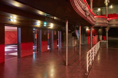 Miniature Amphithéâtre sans fauteuils Intérieur d'une salle de spectacle avec balustrade, colonnes décoratives et éclairage tamisé.
