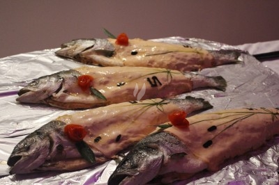 Arrangement floral avec roses blanches, fleurs rouges et feuillage vert, posé sur un cadre rouge sur un sol carrelé.