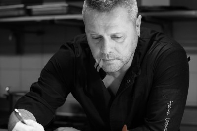 Arrangement floral avec roses blanches, fleurs rouges et feuillage vert, posé sur un cadre rouge sur un sol carrelé.