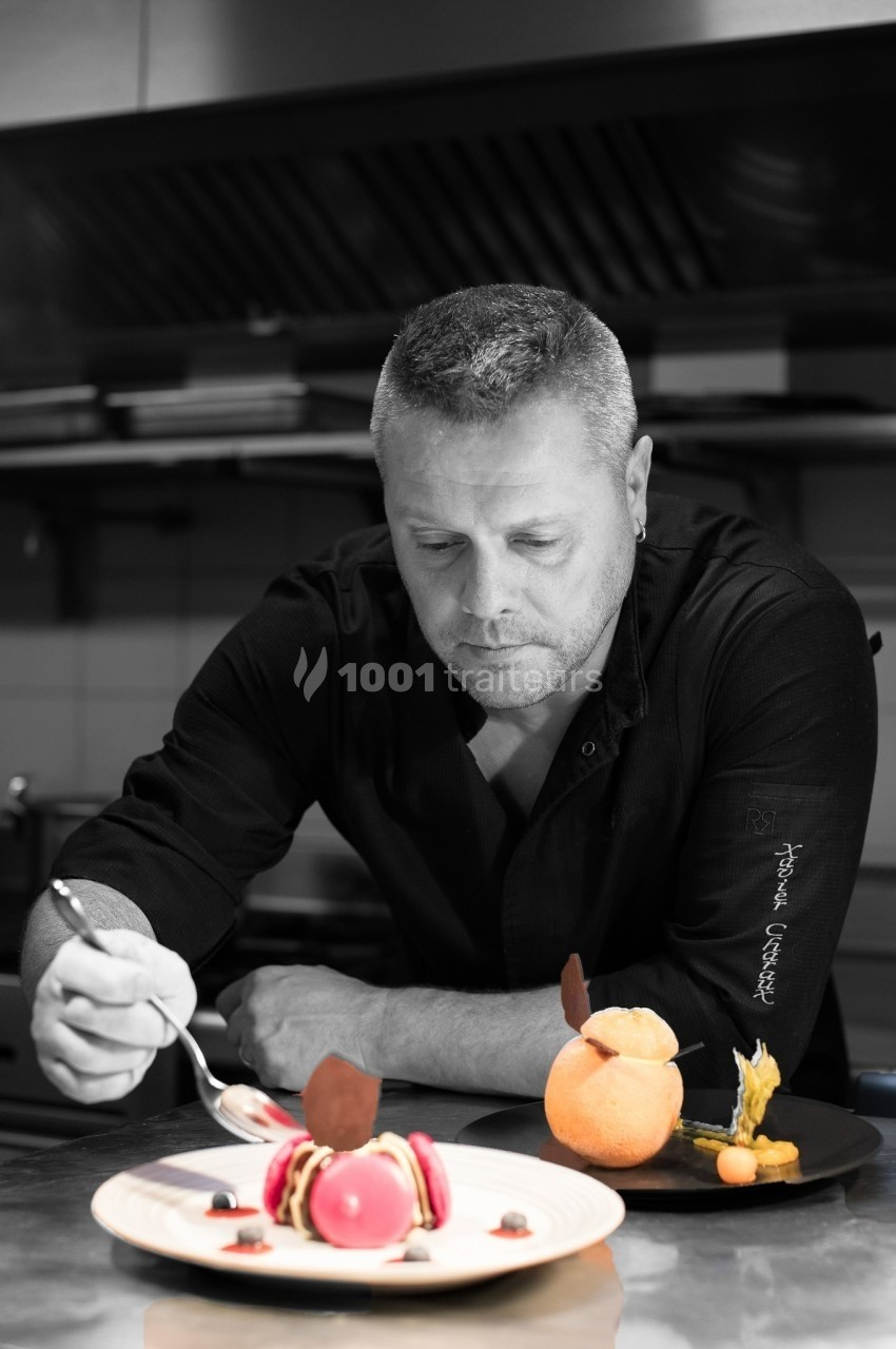 Un chef pâtissier concentré décore un dessert raffiné dans une cuisine professionnelle.