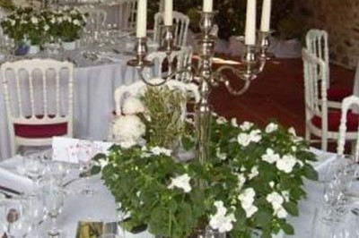 Composition florale avec roses blanches, fleurs rouges et feuillage, disposée sur un cadre rouge sur sol en mosaïque.