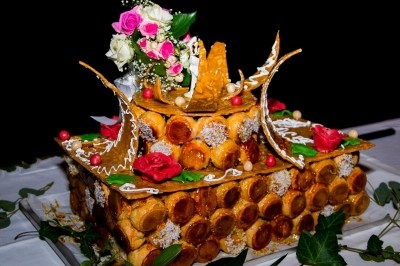 Composition florale avec roses blanches, fleurs rouges et feuillage, disposée sur un cadre rouge sur sol en mosaïque.