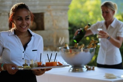 Composition florale avec roses blanches, fleurs rouges et feuillage, disposée sur un cadre rouge sur sol en mosaïque.