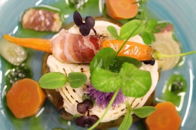 Composition florale avec roses blanches, fleurs rouges et feuillage, disposée sur un cadre rouge sur sol en mosaïque.