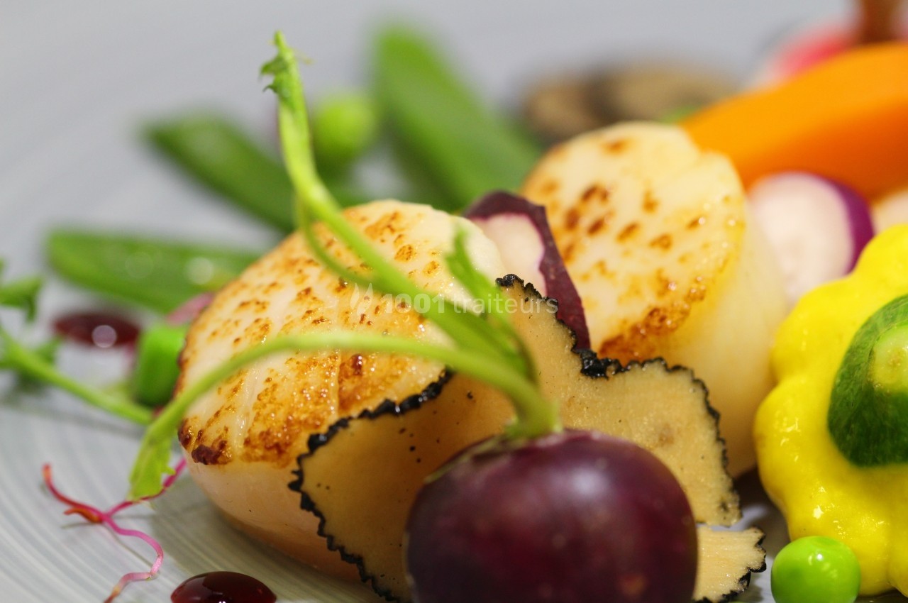 Noix de Saint-Jacques poêlées accompagnées de légumes colorés, truffes et garnitures raffinées.