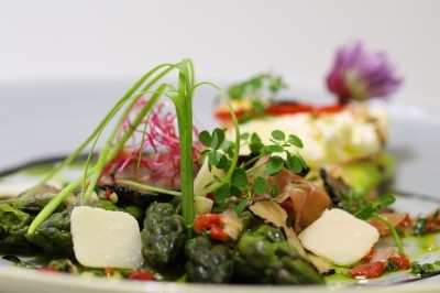 Composition florale avec roses blanches, fleurs rouges et feuillage, disposée sur un cadre rouge sur sol en mosaïque.