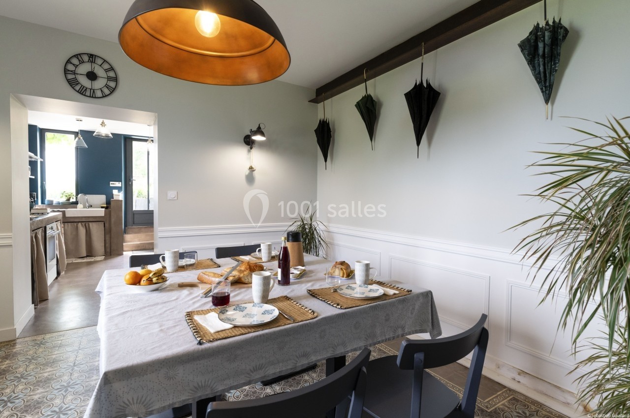 Table dressée pour un petit-déjeuner avec croissants, fruits et boissons dans une salle à manger lumineuse et décorée.
