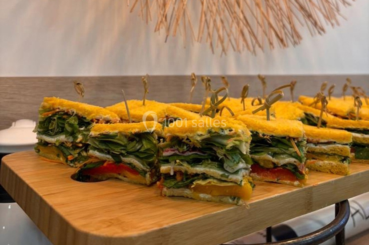 Assortiment de sandwichs végétariens colorés, garnis de légumes et présentés sur un plateau en bois.