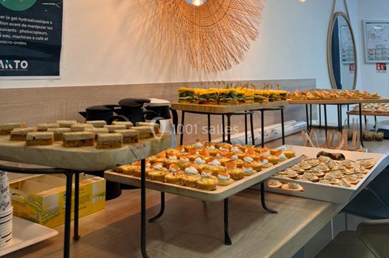 Buffet de canapés variés disposés sur des plateaux dans une salle lumineuse avec un miroir en arrière-plan.