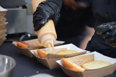 Table ronde dressée pour un repas, avec nappes blanches, couverts, verres, pains et centre de table floral.