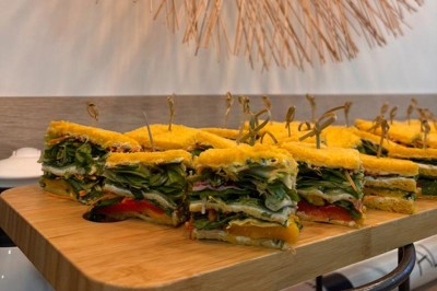 Table ronde dressée pour un repas, avec nappes blanches, couverts, verres, pains et centre de table floral.