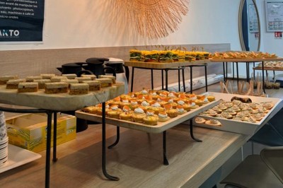Table ronde dressée pour un repas, avec nappes blanches, couverts, verres, pains et centre de table floral.