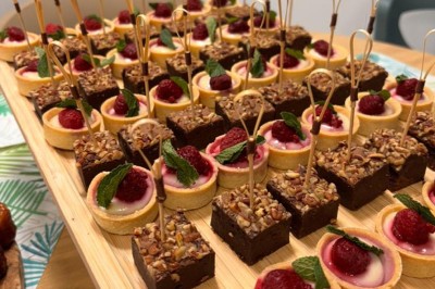 Table ronde dressée pour un repas, avec nappes blanches, couverts, verres, pains et centre de table floral.