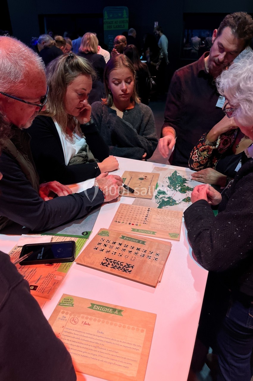 Un groupe de personnes autour d'une table résout des énigmes sur des supports en bois et papier.
