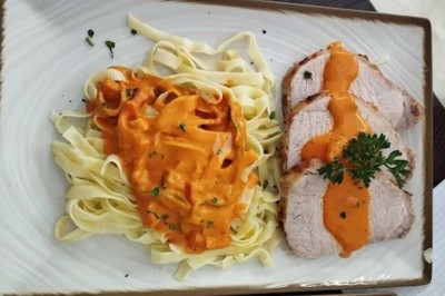 Assiette de salade composée avec feuilles de laitue, tomates, carottes, noix et un morceau de fromage grillé.