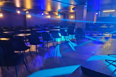 Miniature Location salle Paris 10 (Paris) - Lou Diprey #5 Salle de spectacle avec scène éclairée en bleu, équipée d'un piano, de micros et de chaises devant des tables.
