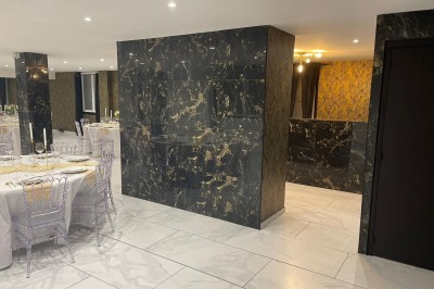 Cuisine professionnelle avec plan de travail en inox, carrelage mural blanc, sol en carrelage gris et équipements basiques.