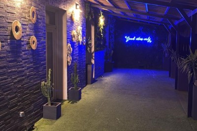 Cuisine professionnelle avec plan de travail en inox, carrelage mural blanc, sol en carrelage gris et équipements basiques.