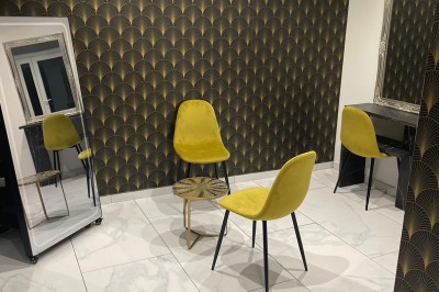 Cuisine professionnelle avec plan de travail en inox, carrelage mural blanc, sol en carrelage gris et équipements basiques.