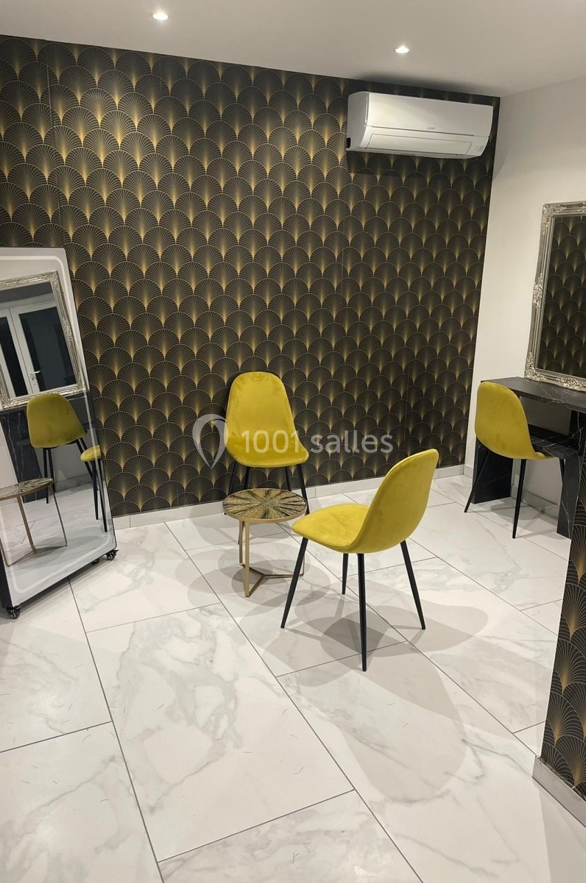 Salle moderne avec murs à motifs dorés, sol en marbre blanc, chaises jaunes, miroir sur pied et coiffeuse.