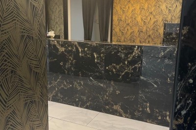 Cuisine professionnelle avec plan de travail en inox, carrelage mural blanc, sol en carrelage gris et équipements basiques.