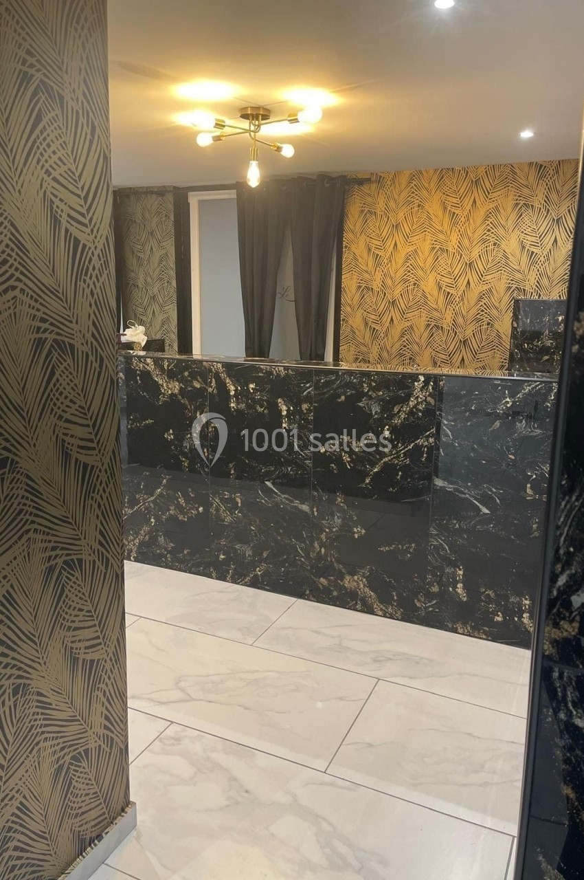 Réception moderne avec comptoir en marbre noir et doré, murs ornés de motifs végétaux dorés et sol en carrelage clair.