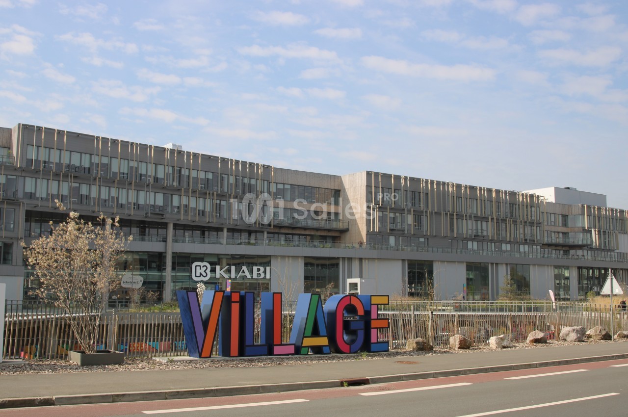 Bâtiment moderne avec le logo ’Kiabi’ et une grande sculpture colorée ’Village’ au premier plan.