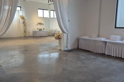 Miniature Location salle Épinay-sur-Seine (Seine-Saint-Denis) - Salle Delena #7 Salle lumineuse avec table ronde dressée, chaises blanches et centre de table floral sous de grandes fenêtres.