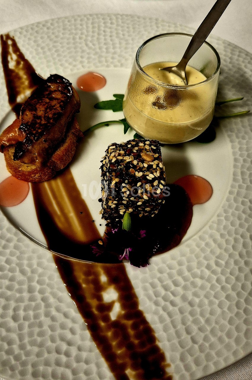 Assiette dressée : tranche poêlée sur pain grillé, bloc enrobé de graines sur sauce brune et mousse en verrine.