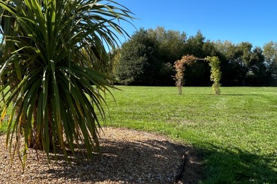 Miniature Location salle Souligné-sous-Ballon (Sarthe) - Le Grand Chêne #12 Deux tonneaux en bois avec parasols sur un sol gravillonné, près d'arbres sous un ciel bleu.
