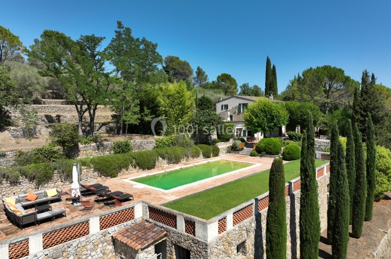 Vue d'une maison en pierre entourée de végétation, avec piscine et terrasse aménagée dans un cadre méditerranéen.