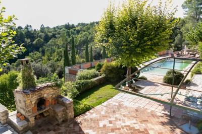 Chambre lumineuse avec lit double, couvre-lit bleu, lampe de chevet et porte-fenêtre donnant sur un jardin.